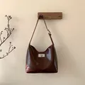 Detalle de bolso hobo de cuero marrón oscuro con cierre de giro plateado y bandolera - Marrón