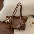 Detail of dark brown leather tote bag with silver eyelets and plush ginger man charm - Brown (With Charm)