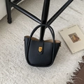 Sac seau chic en cuir grainé noir avec fermoir doré posé sur un tapis en peluche blanc - Noir sans Pendentif