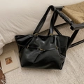 Detailansicht der schwarzen PU-Leder-Einkaufstasche mit goldener Schnalle auf einem Bett - Schwarz