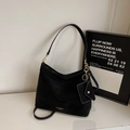 Detail view of black suede tote bag featuring detachable strap and small hanging coin pouch - Black