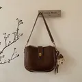 Detail view of brown retro bucket bag with gold square buckle and plush bear charm - Brown With Bear Pendant
