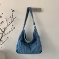 Detailopname van gewassen denim schoudertas met voorvak en metalen drukknoopsluiting - Lichtblauw