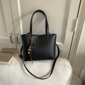 Detail of black lychee grain leather bucket bag with colorful art pendants on white sofa - Black (With Pendant)