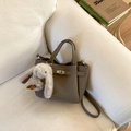 Detailopname van taupe leren emmertas met metalen gesp en pluchen konijnenhanger - Olifantsgrijs met Hanger