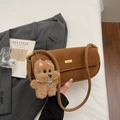 Close-up of retro brown matte underarm bag with gold buckle and plush dog pendant - Brown with Pendant