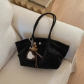 Detail of black suede tote bag with a leopard print heart charm on a cream sofa - Black with Pendant
