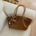 Close-up of brown suede tote bag with leopard bow charm on a cozy beige sofa - Brown with Pendant