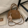 Detail der braunen Vintage-Bowlingtasche aus Leder mit Plüschwelpen-Anhänger auf Teppich - Braun