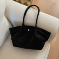 Minimalist black suede tote bag with side buckle straps on a white bouclé sofa - Black without Pendant