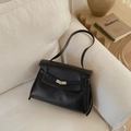 Detail of black lychee grain leather texture and silver metal twist lock on a tote bag - Black