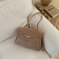 Close-up of khaki leather tote bag with silver metal twist lock on a soft beige sofa - Khaki