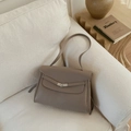 Close-up of taupe litchi grain leather tote bag with elegant silver V-shaped buckle - Gray