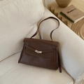 Detail view of dark brown lychee grain leather tote with a silver V-shaped metal buckle - Brown