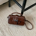Retro small brown square handbag with metal buckle and shoulder strap in lifestyle setting - Brown No Pendant