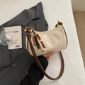 Bolso de hombro media luna crema con borde marrón oscuro y borla de cuentas de madera - Blanco Roto