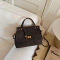 Detalle de bolso de ante gris oscuro con cierre dorado y colgante de llave exclusivo - Marrón