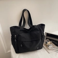 Dettaglio della borsa tote in nylon nero con tasca frontale e coulisse laterali - Nero