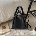 Detail einer schwarzen Eimer-Tasche aus genarbtem Leder mit goldenen Elementen - Schwarz