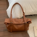 Détail de la texture en cuir marron et des sangles à boucle sur le sac fourre-tout - Marron
