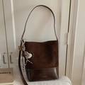 Detailaufnahme der zweifarbigen Eimertasche mit Kontrasttextur und Leopardenherz-Anhänger - Kaffee mit Anhänger