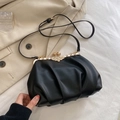 Elegante borsa in pelle nera a pieghe con chiusura a farfalla dorata su un blazer - Nero