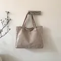 Detail of minimalist beige suede tote bag featuring a round embossed logo and sturdy handles - Khaki