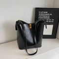 Bolso saco minimalista de cuero negro con acabado pulido y un cierre de giro en color dorado - Negro