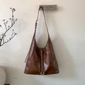 Detalle de bolso tote marrón oscuro con costuras blancas en contraste y un anillo plateado - Marrón