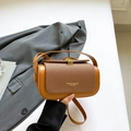 Braune Vintage Quadrat Handtasche aus Textil und Leder auf grauem Blazer drapiert - Braun