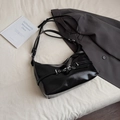 Glossy black hobo shoulder bag with metal eyelets on a minimalist lifestyle setting - Black