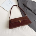 Retro dark brown suede baguette bag with vintage hardware buckle on a white background - Caramel color
