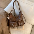 Detail of dark brown vintage Hobo bag with dual front pockets and heart charm on a sofa - With Pendant / Brown
