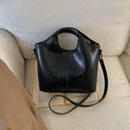 Detail of black matte leather bucket bag featuring circular handle and vertical stitching - No Pendant / Black