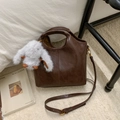 Detail view of dark brown PU leather bucket bag with stitch design and plush bunny charm - With Charm / Brown