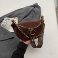 Retro brown suede saddle bag with chunky gold chain and leather strap held by a model - Coffee