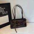 Detail of dark brown leather underarm bag with gold buckle and brand logo - With Charm / Brown