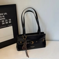 Close-up of black shoulder bag with gold buckle detail and sleek leather texture - With Charm / Black