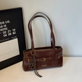 Detailed view of dark brown faux leather shoulder bag with vintage gold buckle and charm - With Charm / Brown