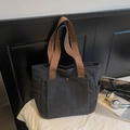 Minimalist black canvas tote bag featuring brown woven straps and spacious front pocket - Black