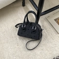 Black mini Boston bag with bow print and leather handles on a beige rug background - Black