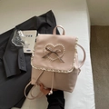 Detailansicht des rosa Lederrucksacks mit weißer Spitze und Perlenherz mit Karoschleife - Rosa