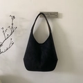 Detail of minimalist black hobo bag in matte suede hanging on a wall hook - Black