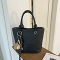 Black lychee grain bucket bag with baseball charm and top handles in lifestyle setting - With Baseball Pendant / Black