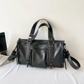 Black moto-style tote bag with silver studs and multiple zipper pockets in an office setting - Black