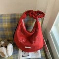 Detailaufnahme einer roten Plüschtasche mit Vogelbestickung auf einem gemütlichen Sofa - Rot