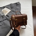 Details der braunen Kunstlederstruktur und der goldenen Metallschnallen der Tasche - Kaffeebraun
