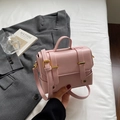 Detailansicht der rosafarbenen quadratischen Handtasche mit goldenen Beschlägen und Riemen - Rosa