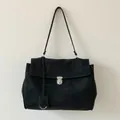 Detalle de bolso tote de ante negro con hebilla plateada redonda y diseño minimalista - Negro