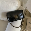 Detail of black leather crossbody bag with golden square lock and metal chain on a sofa - Retro Small Square Bag / Black (PU Glossy)